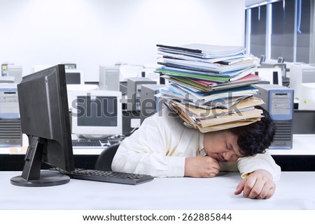 Portrait of overwhelmed fat man sleeping in office with documents on his head