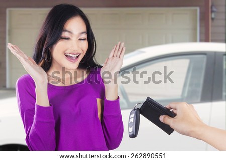 Portrait of teenage girl looks happy get a new car in the garage at home
