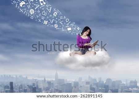 Female student sitting on the cloud while using a digital tablet to share information
