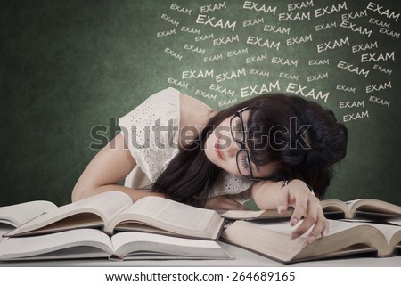 Portrait of tired female student preparing exam and sleep over the textbooks