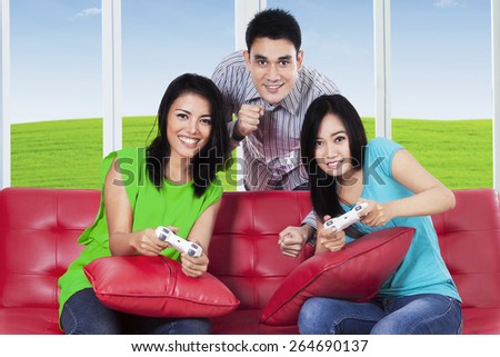 Portrait of group of teenager playing video games with joystick while sitting on the couch at sofa