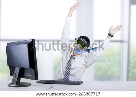 Portrait of businessman wearing a snorkeling mask and expressing success in the office