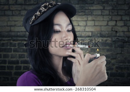 Portrait of a beautiful bad girl lighting up a cigarette with a match