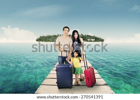 Portrait of attractive family arriving at resort and standing at resort bridge with their luggage