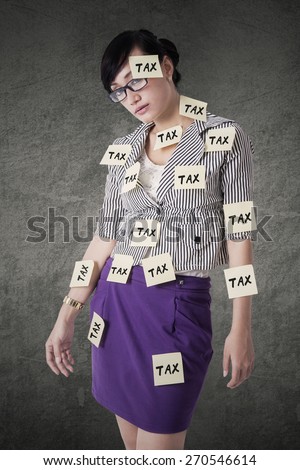 Young female worker with paper notes to remind tax time attached on her body