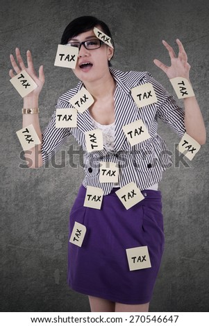 Young asian manager looks stressed with paper notes attached on her body to remind tax time