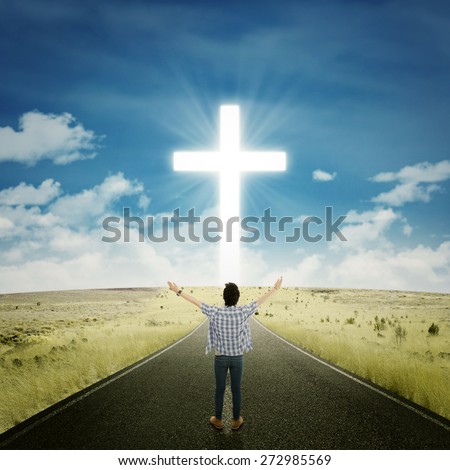 Rear view of young man standing on the road and raise his hands to worship on the GOD