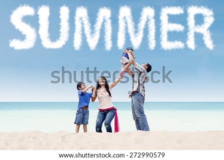 Two asian parents playing with their children on the tropical shore under a summer\'s cloud