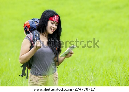 Portrait of female hiker using a smart phone on the meadow to see the direction when hiking