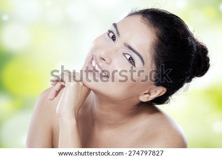 Beauty face of young female model with smooth skin after skincare, smiling at the camera on blur background