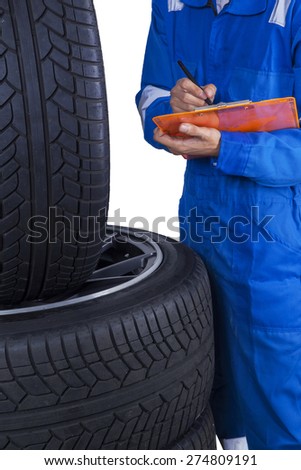 Closeup of male mechanic with a blue uniform checks tires condition and write the report on the clipboard