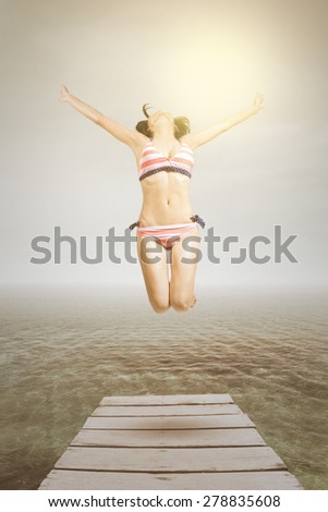 Attractive woman wearing swimwear enjoy freedom and jump at pier, shot with an instagram effect