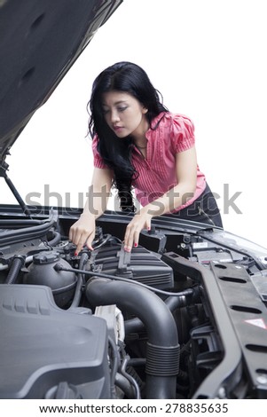 Portrait of young woman checks the machine of a broken car, isolated on white