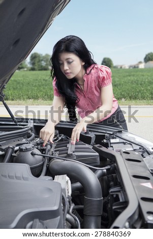 Portrait of a pretty woman checking a broken car alone on the road