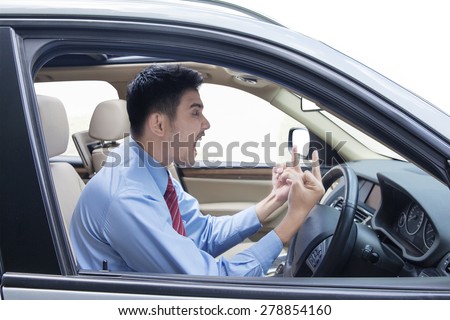 Portrait of young entrepreneur looks angry in the car while showing two middle fingers and shouting