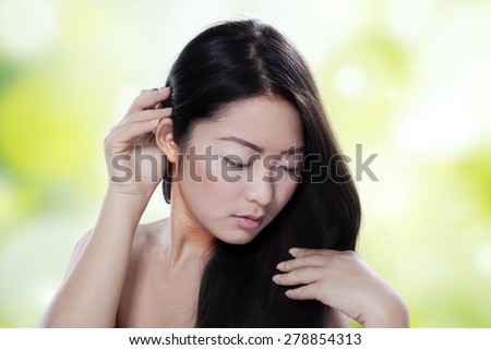 Attractive chinese female model with long black hair in front of light glitter background