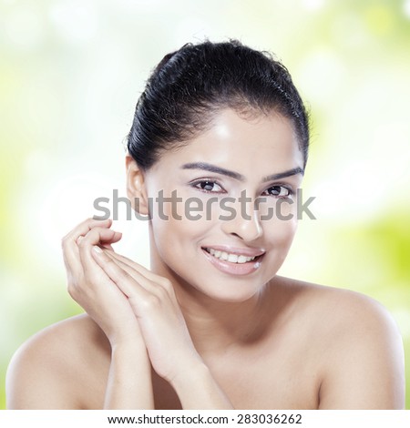 Lovely young model with fresh skin after skin treatment, smiling at the camera on bokeh background