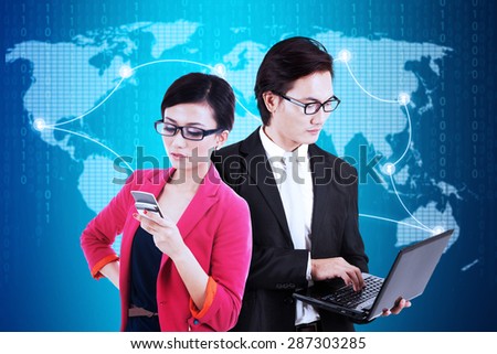 Young businesspeople using laptop computer and mobile phone to communicate with their partners