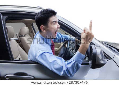 Young man driving a car and looks angry, screaming and showing middle finger