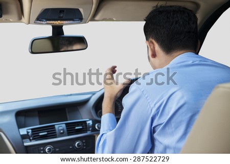 Rear view of young man driving a car and looks angry, shouting inside the car