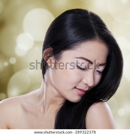 Portrait of asian woman with healthy perfect skin and black hair against bokeh background