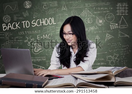 Portrait of teenage student with black hair studying in the class while using a laptop