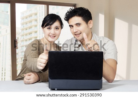 Happy couple and laptop showing thumbs up, shot at home