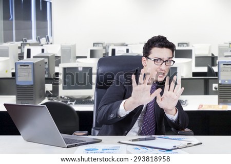 Young businessman with scared expression working in the office with laptop and business chart