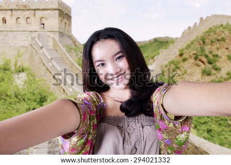 Attractive young girl enjoy traveling and taking self picture at Great Wall of China