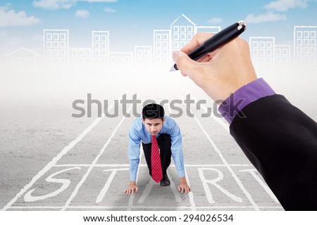 Male entrepreneur kneeling on the start line with hand drawing the start line