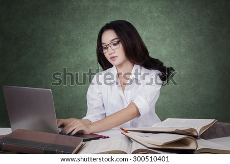 Portrait of cute female student with long hair using laptop computer to study in the classroom