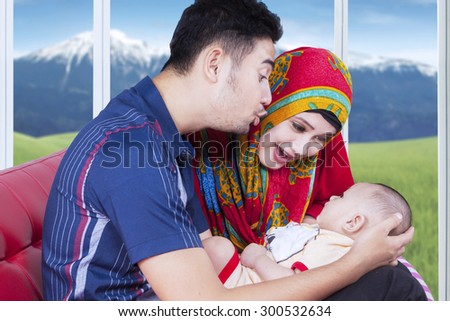 Male baby lying on the father\'s hands and playing with dad and mom, shot at home