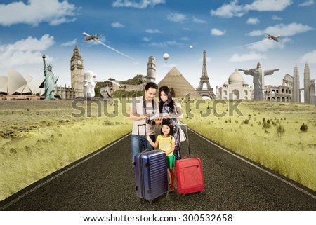Tourist standing on the road with luggage and use digital tablet to see the famous place. Shot with famous landmarks on the back