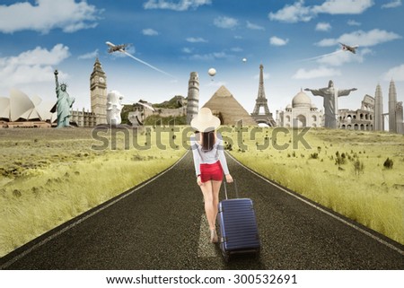 Rear view of woman walking on the road while carrying luggage to the famous landmarks
