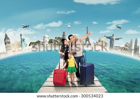 Two young parents with their daughter carrying bags to holiday on the world monument