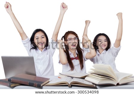 Group of three excited teenage high school students expressing success and raise hands together, isolated on white background