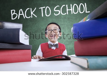 Cheerful little boy back to school and smiling in the class while wearing uniform and studying