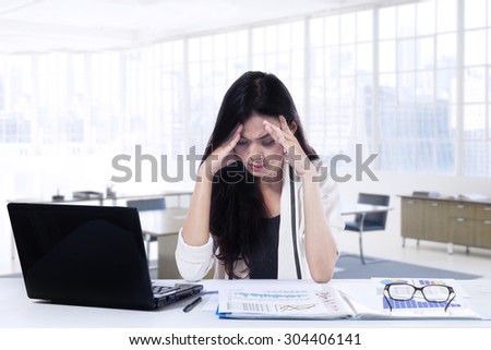 Portrait of female entrepreneur sitting in the office while doing her job and looks confused