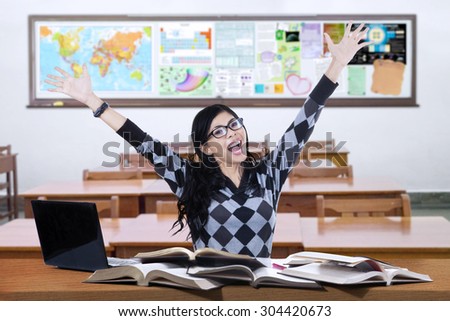 Portrait of happy female student studying in the classroom and raise hands