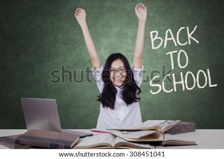 Portrait of cheerful teenage student back to school and raise hands in the classroom