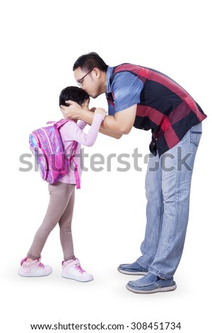 Concept of back to school with a young father kissing his daughter before go to school. Isolated on white background