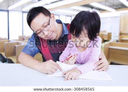Portrait of female student studying with male teacher in the classroom and try to write