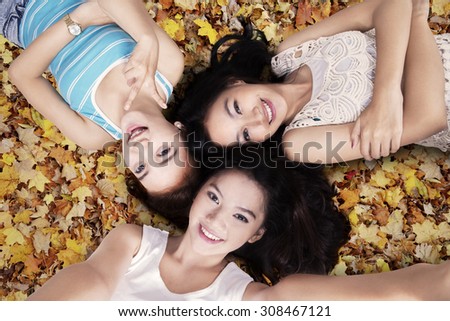 Closeup of teenage girls lying down on the autumn leaves and taking self picture together