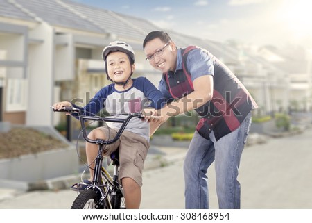 Portrait of happy father teach his son to drive a bicycle on the road, shot outdoors