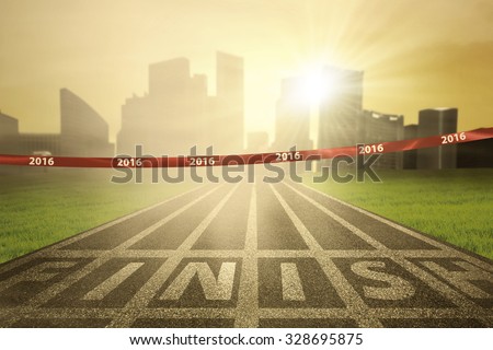 Image of an empty finish line with numbers 2016 on the tape and bright sun rays at the end of track