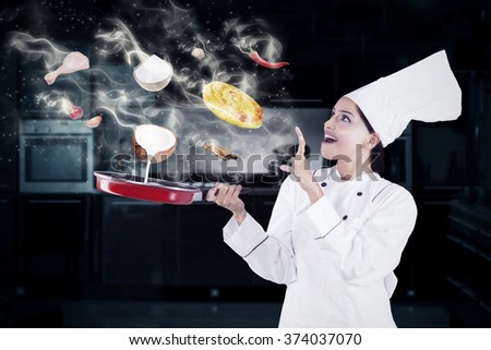 Indian female chef cooking in the kitchen with magic while wearing chef uniform