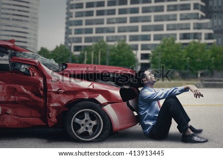 Image of stressful man sitting in front of a broken car after traffic accident on the road