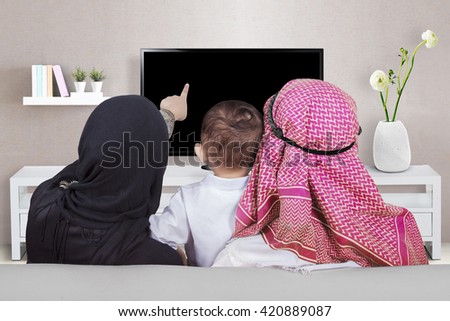 Back view of muslim family enjoy leisure time together while watching television in the living room