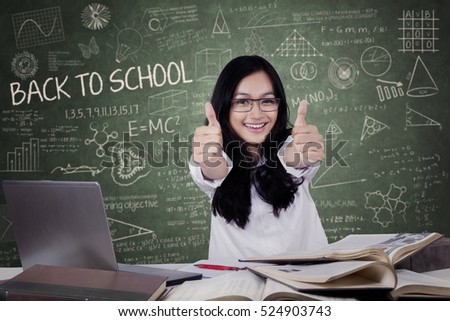Joyful teenage student with black hair back to school and show thumbs up in the class