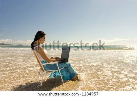 Asian woman with laptop working at the beach